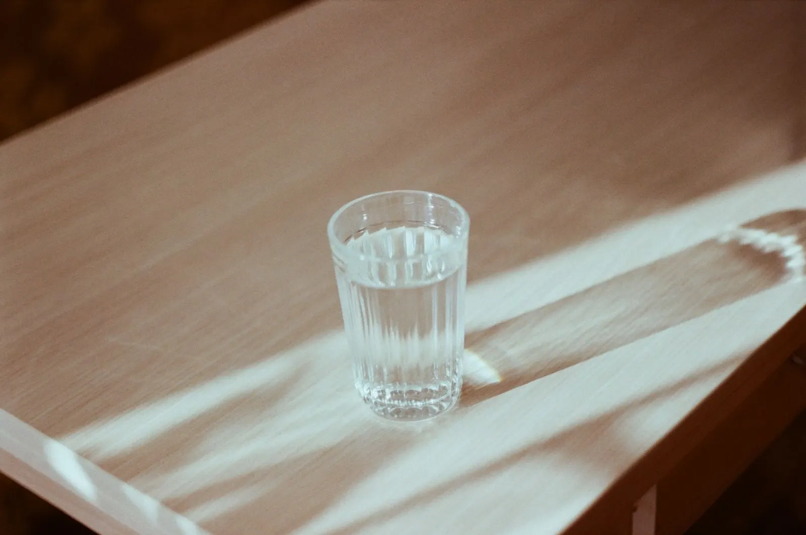 A glass of water on a wooden table in soft light