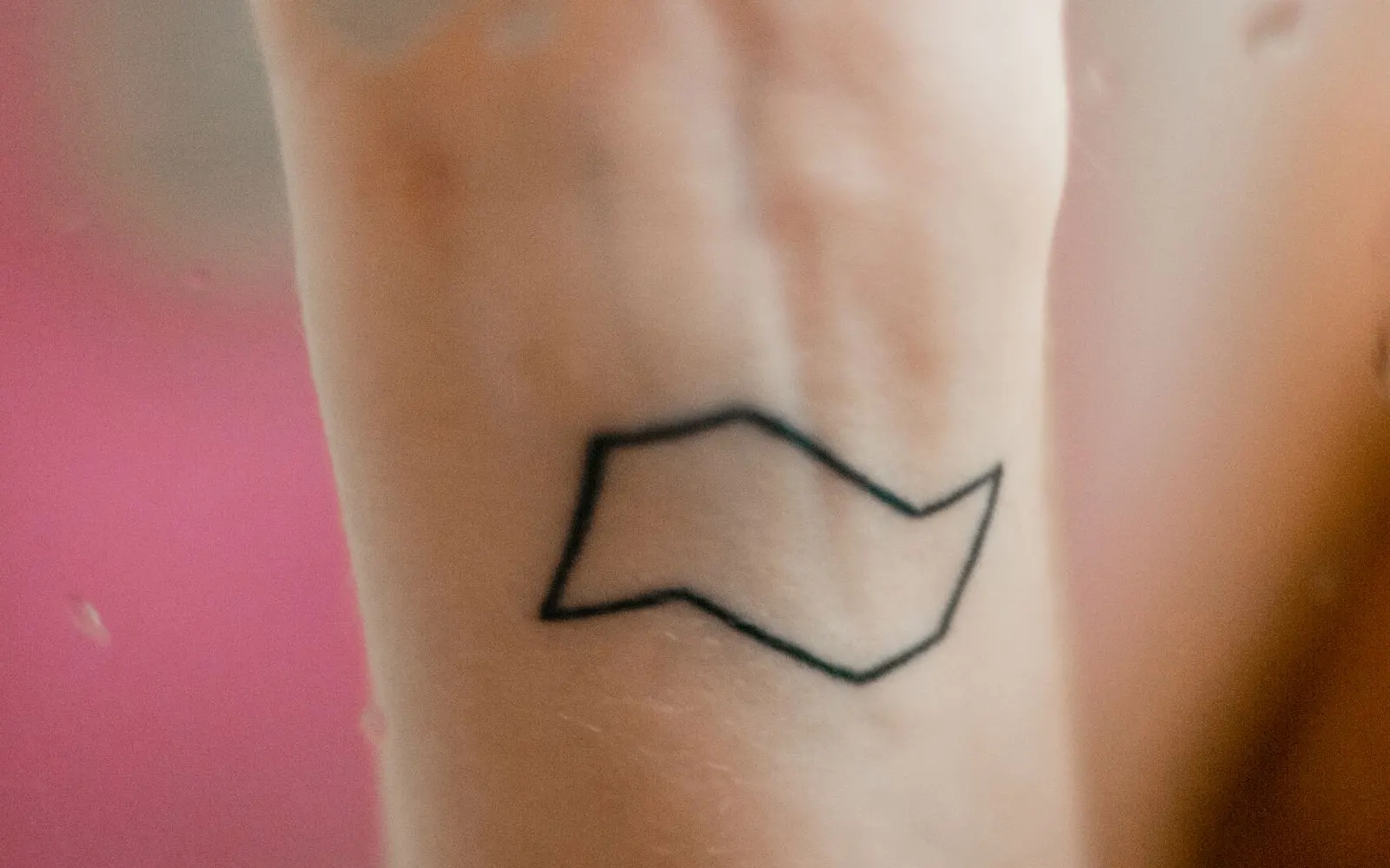 A small black-ink geometric tattoo on a forearm