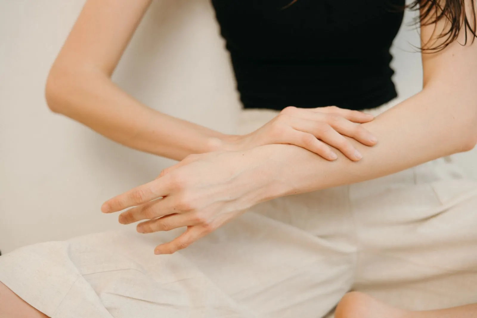 A woman resting a hand on her bare forearm