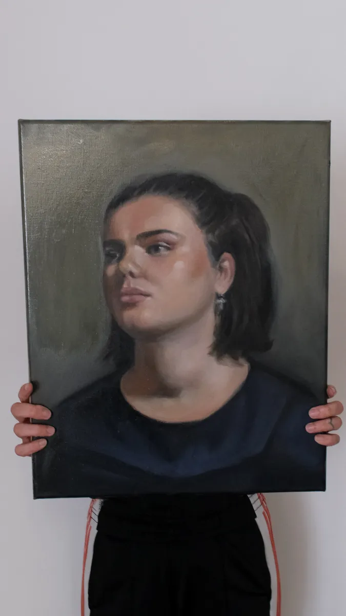 Oil portrait of a young woman looking to one side, held up by Britt Beale